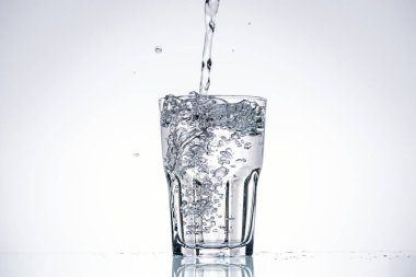 water pouring in drinking glass on white background with backlit and copy space clipart