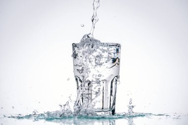 water pouring in full glass on white background with backlit and splashes clipart