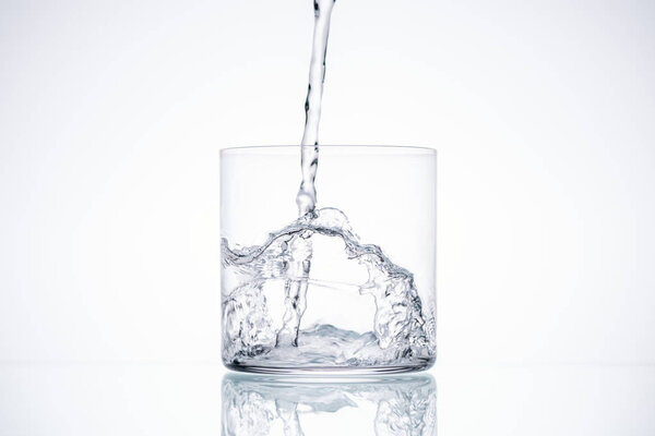 water pouring in glass on white background with backlit and copy space