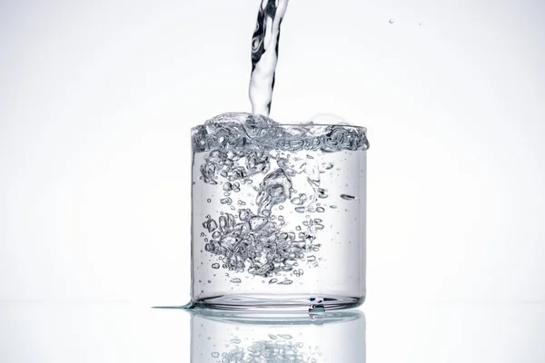 Acqua Versando Vetro Sfondo Bianco Con Retroilluminazione Spazio Copia — Foto Stock