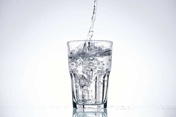 water pouring in drinking glass on white background with backlit and copy space