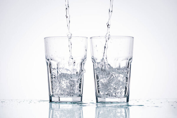 water pouring in glasses on white background with backlit
