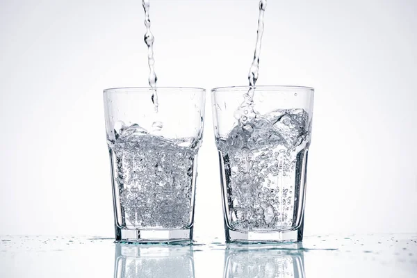 Water Pouring Glasses White Background Backlit Splashes — Stock Photo, Image