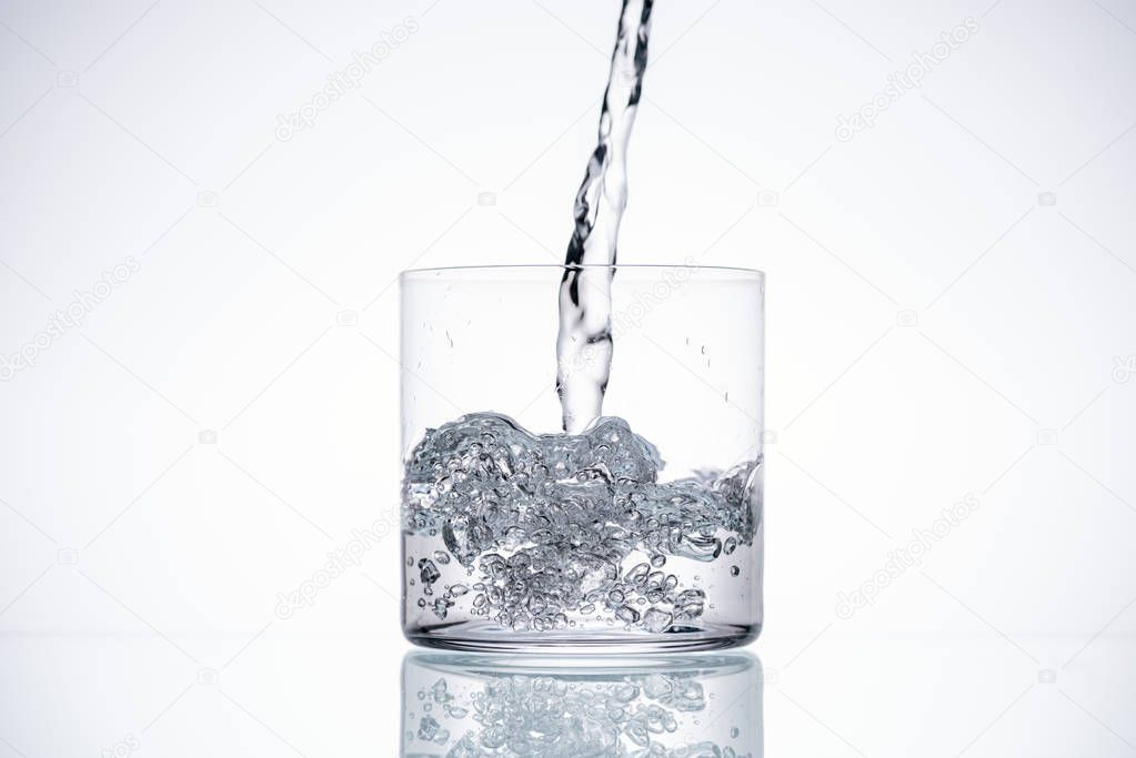 water pouring in glass on white background with backlit and copy space