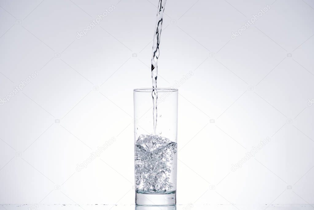 water pouring in glass on white background with back light and copy space