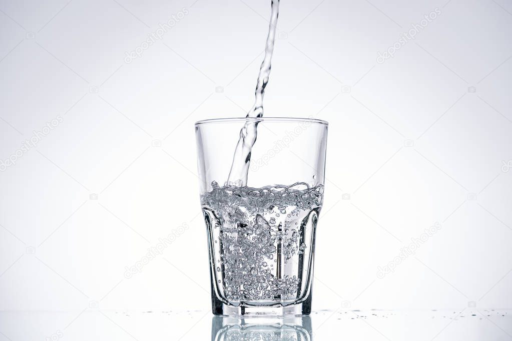 background of water pouring in glass on white with backlit