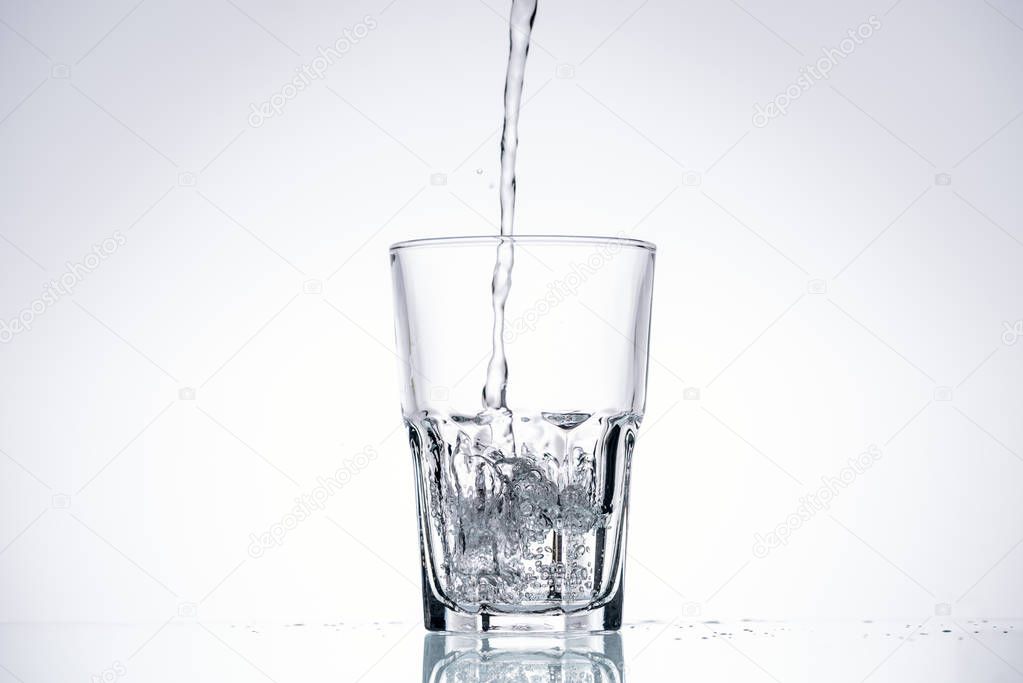 background of water pouring in glass on white with backlit