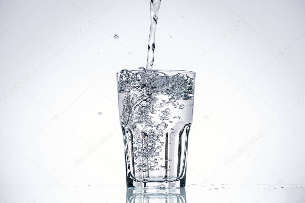 water pouring in drinking glass on white background with backlit and copy space