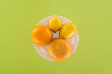 Yeşil izole beyaz tabakta bütün portakal ve greyfurt limon yakınındaki Üstten Görünüm