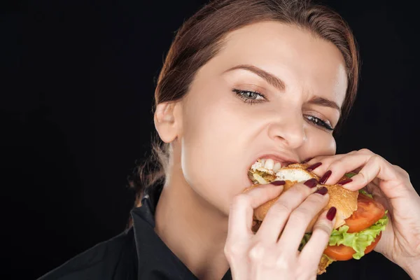 愤怒的妇女吃美味的鸡肉汉堡孤立的黑色 — 图库照片