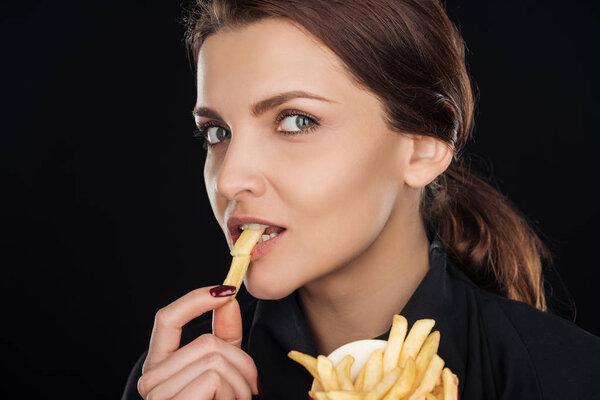 attractive while eating tasty french fry isolated on black