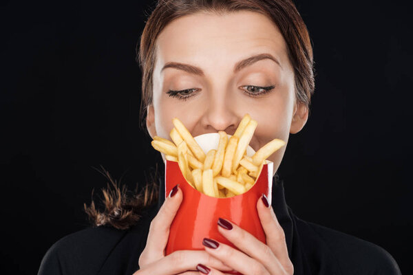 woman looking at french fries isolated on black