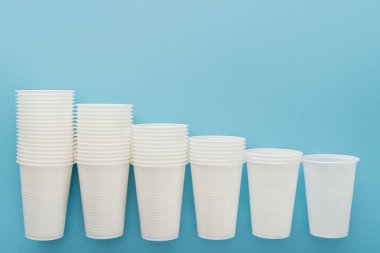 flat lay with white plastic cups on blue background with copy space  clipart