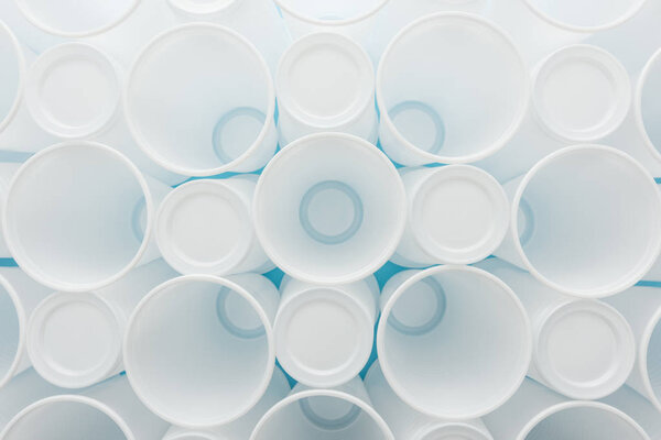 вид сверху на белый и пластиковый стаканчики на синем фоне
 