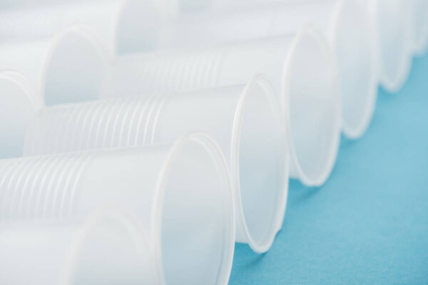 selective focus of white plastic cups on blue background with copy space 