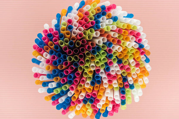 top view of colorful and bright plastic straws isolated on pink