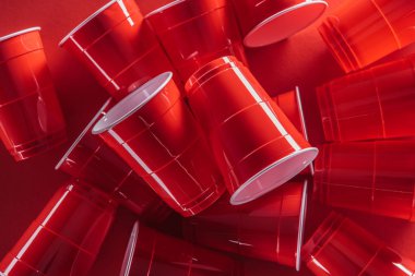 parlak ve renkli plastik bardak kırmızı zemin üzerine yukarıdan 