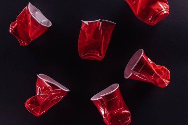 top view of bright and colorful, red plastic cups isolated on black clipart