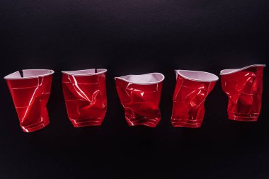 top view of bright and colorful, red plastic cups isolated on black clipart
