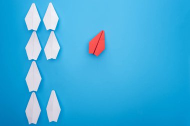 Flat lay with white and red paper planes on blue clipart