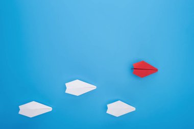 Flat lay with white and red paper planes on blue clipart