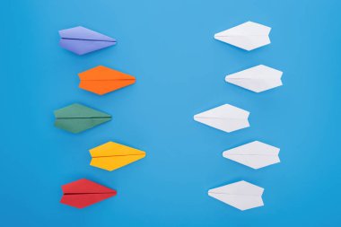 Flat lay with colorful paper planes on blue surface clipart