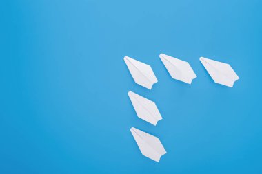 Flat lay with white paper planes on blue surface clipart