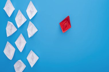Flat lay with white and red paper boats on blue surface clipart
