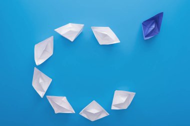 Flat lay with white and blue paper boats on blue clipart