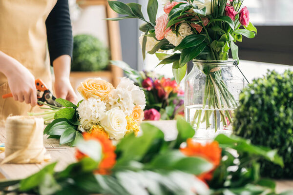Cropped view of florist cutting off flower stalks with pruning shears