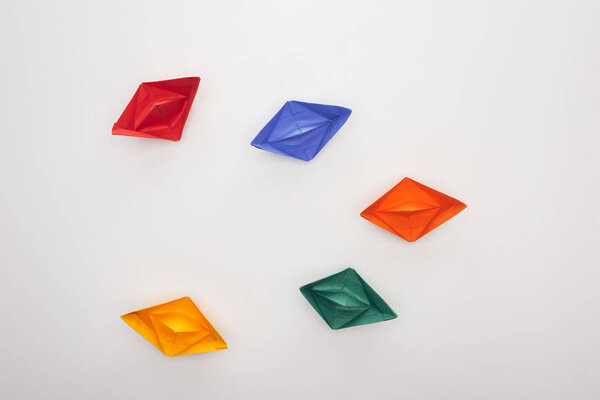 Top view of colorful paper boats on white surface