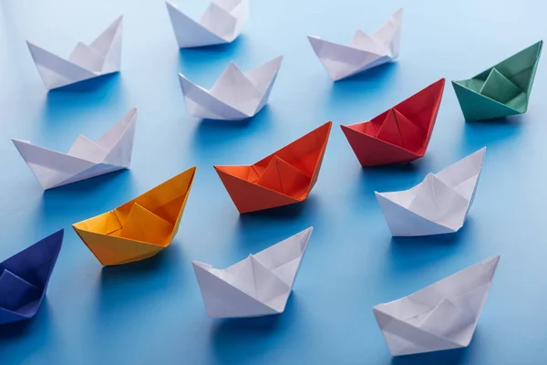 stock image Colorful bright paper boats on light blue surface