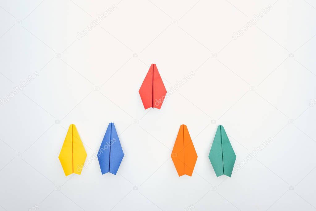 Flat lay with colorful paper planes on white surface
