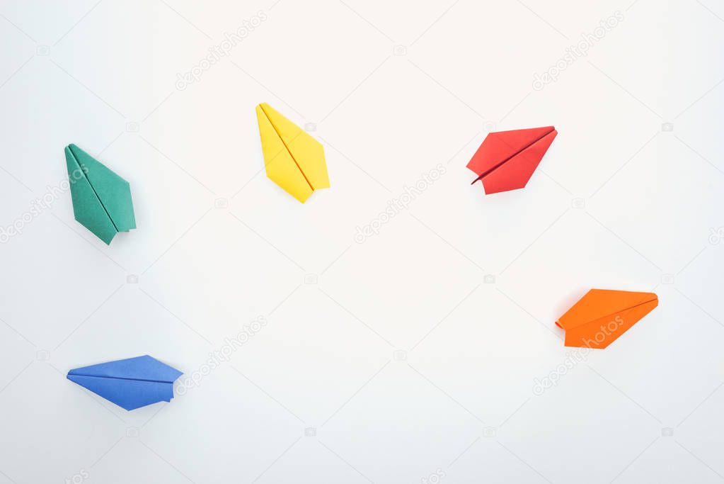 Top view of colorful paper planes on white surface
