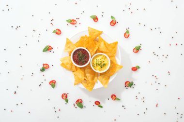 tabak, baharat ve fesleğen yaprakları ile dilimlenmiş Chili biber üzerinde lezzetli nachos ve soslar üst görünümü