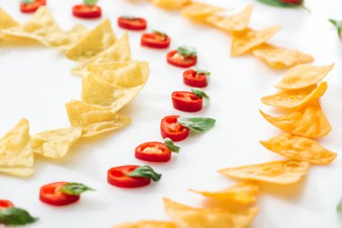 Beyaz arka planda fesleğen ile lezzetli nachos ve Chili Peppers seçici odak 