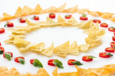 Beyaz arka planda fesleğen ile lezzetli nachos ve Chili Peppers seçici odak 