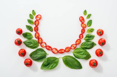 Düz kesilmiş Chili biber, fesleğen yaprakları ve kopya alanı ile beyaz arka planda olgun kiraz domates ile yatıyordu 