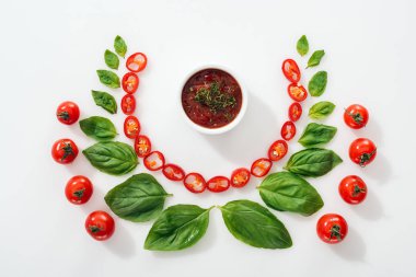 Beyaz arka planda kesilmiş Chili Peppers, fesleğen yaprakları, sos ve olgun kiraz domates ile düz yatıyordu 