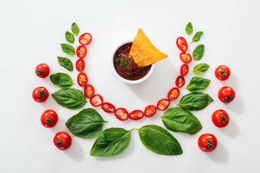 Düz kesilmiş Chili biber, fesleğen yaprakları, sos ve olgun kiraz domates nachos ile yatıyordu
