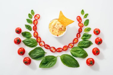 top view of cut chili peppers, basil leaves, nachos in sauce and ripe cherry tomatoes clipart