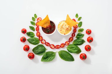 kesilmiş Chili Peppers üst görünümü, fesleğen yaprakları, soslar ve olgun kiraz domates nachos