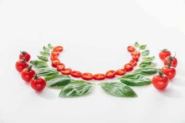 Beyaz arka planda kesilmiş Chili Peppers, fesleğen yaprakları ve olgun kiraz domates ile düz yatıyordu 