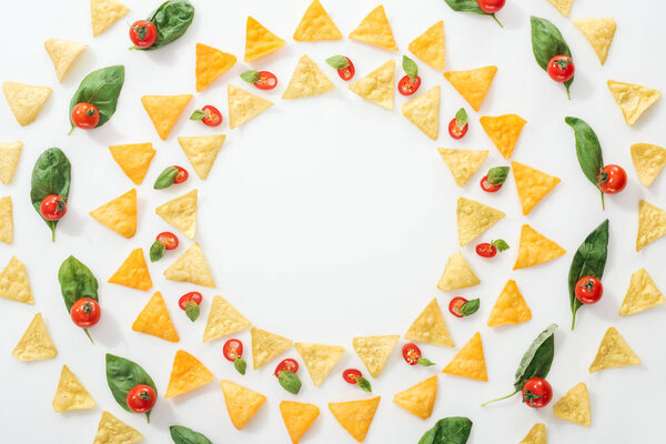 top view of tasty nachos and sliced chili peppers with basil and cherry tomatoes on white background 