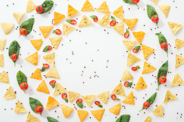 flat lay with tasty nachos, spices and sliced chili peppers with basil and ripe cherry tomatoes