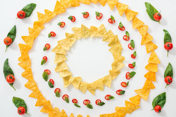 top view of sliced chili peppers and tasty nachos with basil leaves and cherry tomatoes