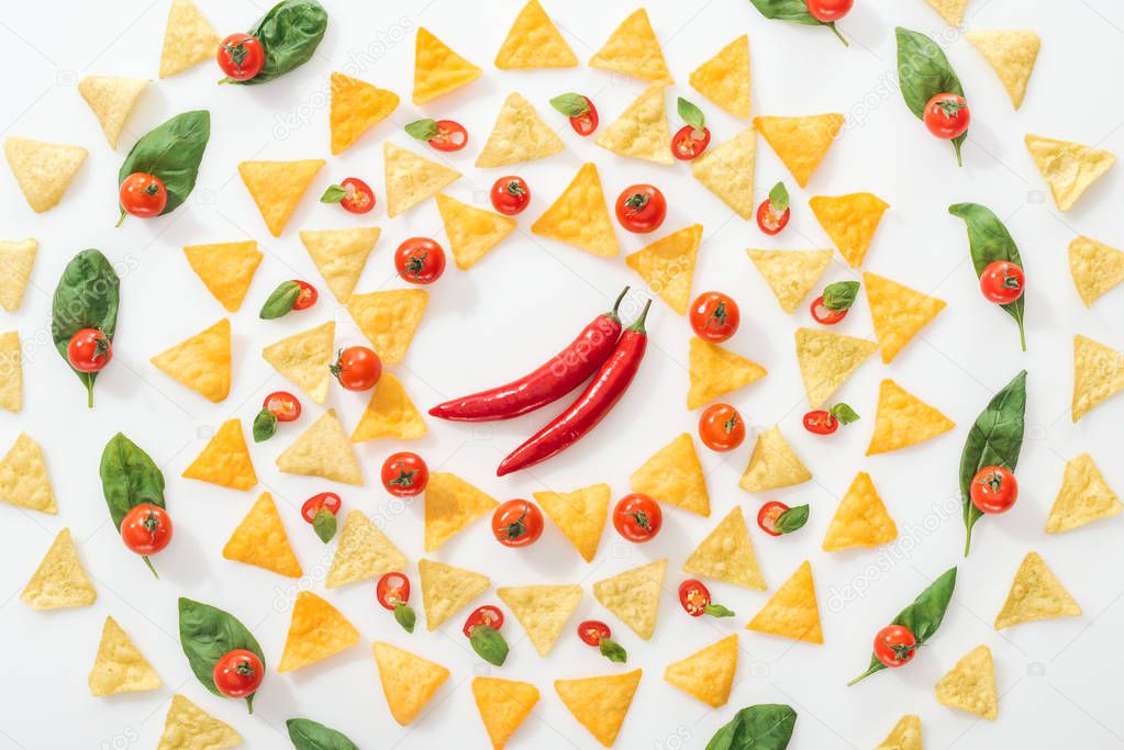 flat lay with tasty nachos and sliced chili peppers with basil and cherry tomatoes on white background 