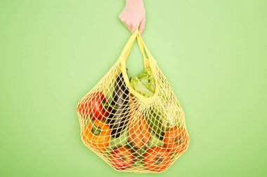 cropped view of woman holding string bag with raw vegetables clipart