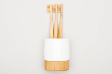 natural bamboo toothbrushes in stand on grey background clipart
