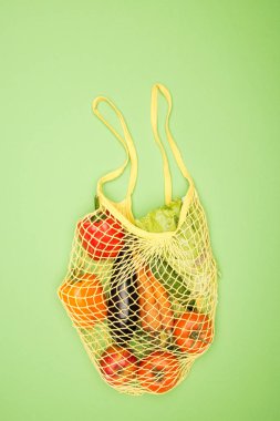 Açık yeşil yüzeyde olgun organik sebzeler ile sarı dize çanta üst görünümü